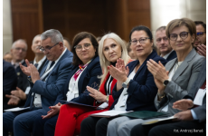 Widzowie siedzący na krzesłach biją brawo